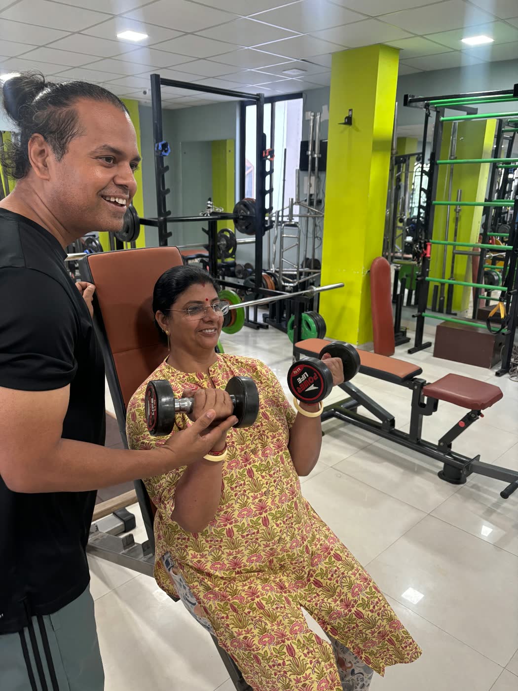 Vincy coaching a member through a seated dumbbell curl at Vincy's Gym